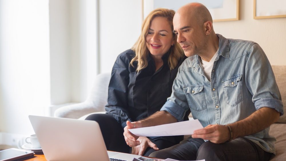 Cheerful mature couple having video call via laptop. Cheerful middle aged people talking about house renovation through video call. New house project, renovation concept