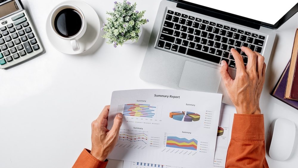 Business man hands working on business data to discuss information with calculator,laptop,cup of coffee,mouse,book on modern white desk table at office.