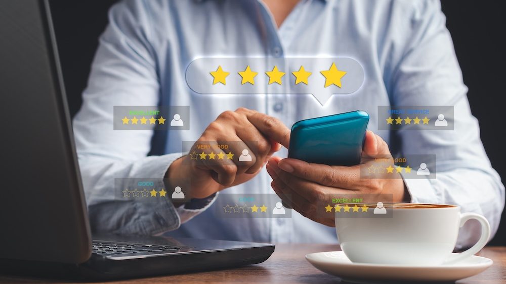 Man using a smartphone give the five-star icon a rating of very impressed for service. Customer service and satisfaction surveys concept